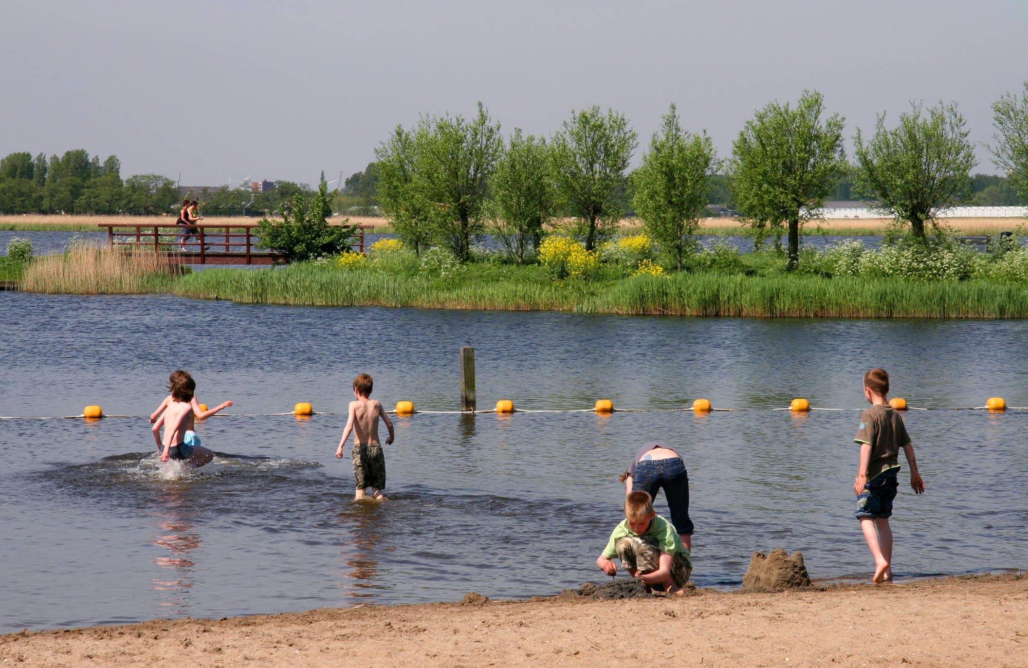 Kinderen spelend in het water en op een strandje.